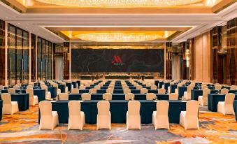 There are rows of blue chairs set up in a large ballroom for an event or formal function at Yiwu Marriott Hotel