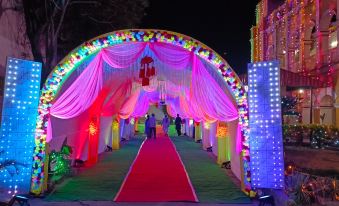 a large , colorful archway decorated with lights and flowers , set against a dark background at Hotel Samrat