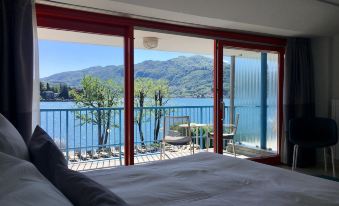 a bedroom with a large bed and a view of a lake through the window at Hotel l'Approdo