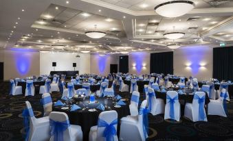a large banquet hall is set up for a formal event , with tables and chairs arranged in an elegant manner at Mercure Telford Centre Hotel