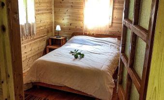 a cozy wooden cabin bedroom with a large bed , two nightstands , and a window at Farma Sotira