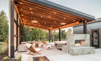 a modern outdoor living space with a wooden roof , stone floor , and hanging lights under a covered patio at Lodges on Vashon