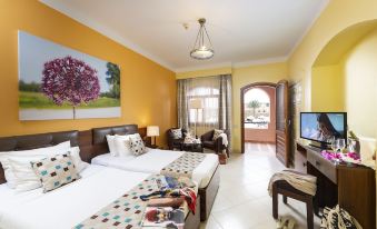 a hotel room with two beds , a couch , and a tv , all set against yellow walls at Three Corners Rihana Resort El Gouna