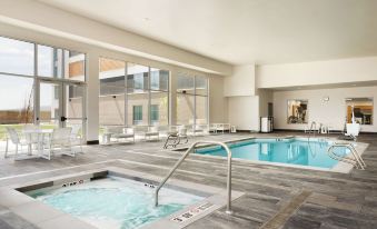 a large swimming pool with a spa in the middle , surrounded by lounge chairs and benches at Homewood Suites by Hilton Salt Lake City Draper