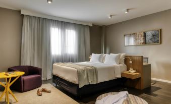a hotel room with a king - sized bed , a chair , and various items on the table at Mercure Belo Horizonte Vila da Serra
