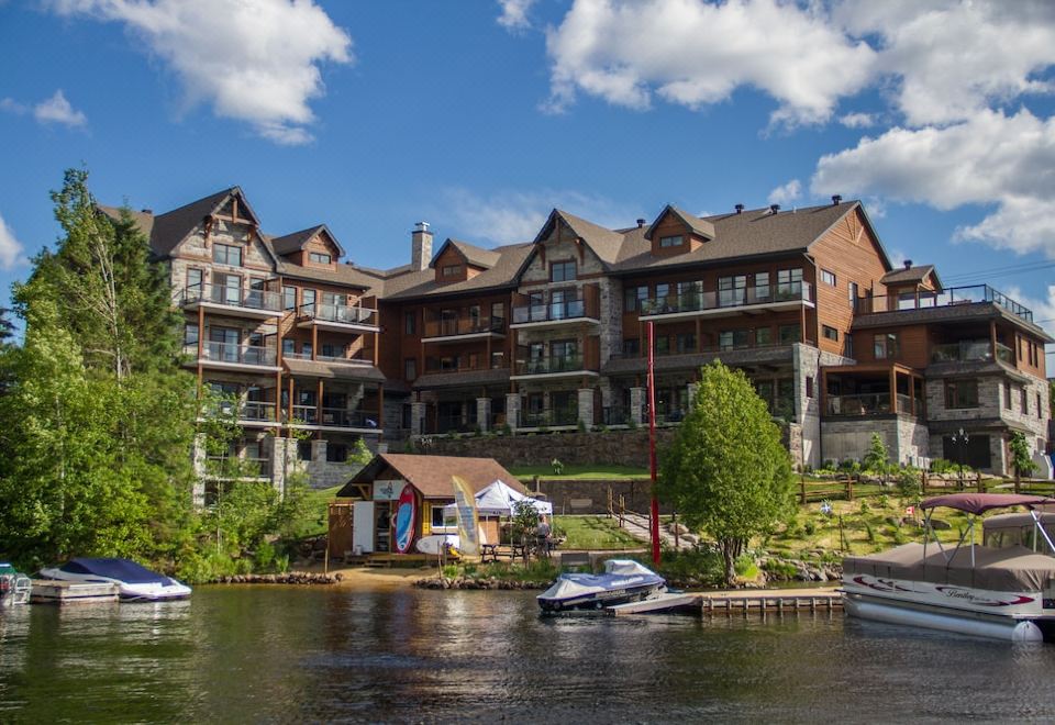 a large , multi - story building is situated on the shore of a lake with boats docked nearby at Le Viking Resort & Marina