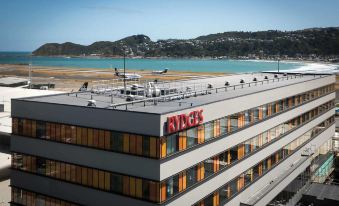 "a large building with the word "" ricc "" on it is overlooking a lake and mountains" at Rydges Wellington Airport, an EVT hotel