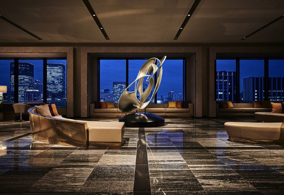 a luxurious hotel lobby with large windows , a marble floor , and modern furniture , including a sculpture in the center at The Royal Park Hotel Iconic Osaka Midosuji