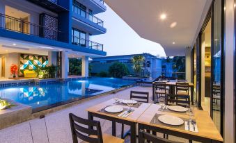 an outdoor dining area with tables and chairs set up near a swimming pool , surrounded by a building at AVA SEA Resort Krabi