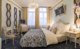 a luxurious bedroom with a king - sized bed , a flat - screen tv mounted on the wall , and a chandelier hanging from the ceiling at Hotel Alexandra
