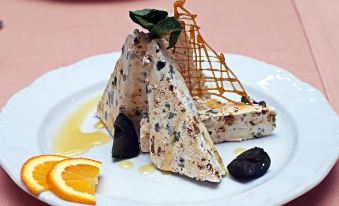 a white plate with a dessert on it , topped with orange slices and black olives at Festa Winter Palace Hotel