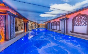 a large swimming pool with blue water is surrounded by a building with white walls and red trim at Kapadokya Hill Hotel & Spa (12+)