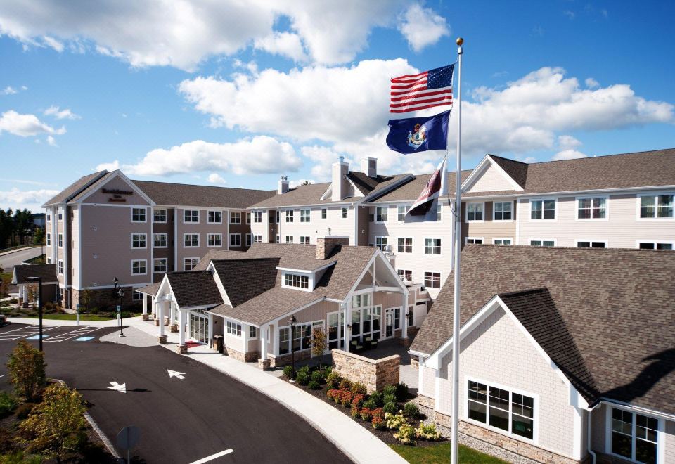 an american flag flying in front of a large building , possibly a hotel or apartment complex at Residence Inn Auburn