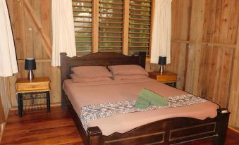 a large bed with a wooden headboard and footboard is in a bedroom with wooden floors at Rainforest Eco Lodge