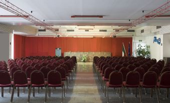 a large conference room with rows of red chairs arranged in a symmetrical fashion , ready for a meeting or presentation at Hotel Califfo
