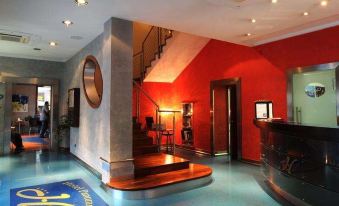 a hotel lobby with a red reception desk , blue carpet , and a staircase leading to the second floor at Panorama Hotel