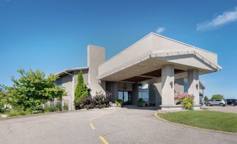 a modern , gray building with a curved entrance and multiple columns , surrounded by trees and plants at Best Western Pembroke Inn  Conference Centre