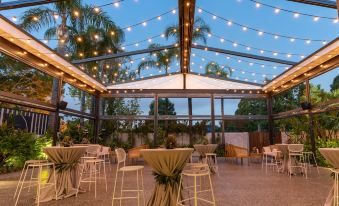 a large outdoor event space with a glass roof and tables , chairs , and string lights at Marion Hotel