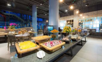 a modern dining room with a long buffet table filled with a variety of food items , including fruits , vegetables , and desserts at Beyond Patong