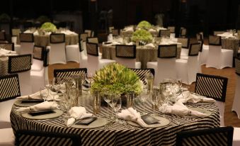 a well - arranged event hall with tables covered in black and white checkered tablecloths , along with chairs arranged around them at Heritance Kandalama