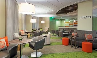 a modern hotel lobby with various seating options , including couches and chairs , as well as a dining area at Even Hotel Rockville - Washington, DC Area, an IHG Hotel