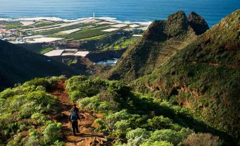 a person walking on a mountain trail , surrounded by lush greenery and a beautiful landscape at Landmar Costa Los Gigantes