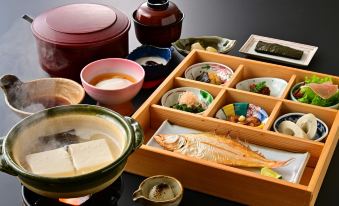 a wooden tray filled with various types of sushi , including rolls , nigiri , and sashimi , placed on a dining table at Yamadaya