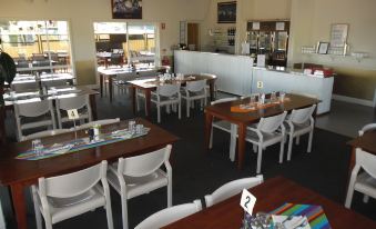 a dining room with white tables and chairs , some of which are covered in tablecloths at Coolgardie GoldRush Motels