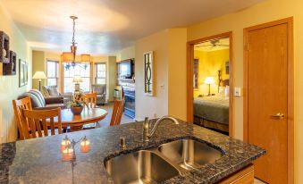 a kitchen with a sink , dining table , and living room in the background , all decorated in yellow at Newport Resort
