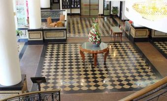 a grand foyer with a checkered floor , a chandelier hanging from the ceiling , and a staircase leading up to the second floor at Good Hope Hotel