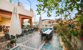 an outdoor dining area with several tables and chairs , some of which are covered by umbrellas at Grand Hotel Madaba