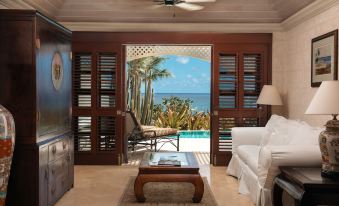 a room with a couch , table , and sliding doors leading to a pool and ocean at The Crane Resort