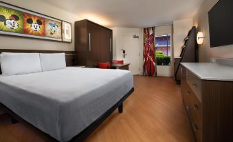 a hotel room with a large bed , wooden flooring , and a window with a red curtain at Disney's All-Star Music Resort