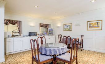 a dining room with a table surrounded by chairs , and a television mounted on the wall at The Farmington Inn and Suites