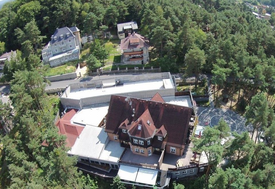 aerial view of a large house surrounded by trees , with a car parked in front of it at Hotel Berg