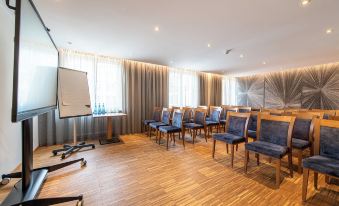 a large room with wooden floors and chairs arranged in rows , ready for a meeting or presentation at Hotel Post Alpine Cityflair