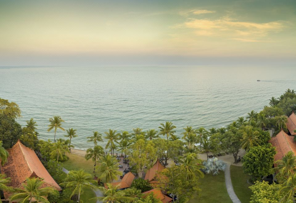 aerial view of a tropical beach with palm trees , boats in the water , and buildings in the distance at Anantara Hua Hin Resort