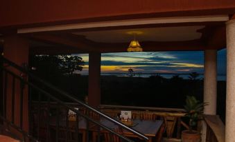 a room with wooden tables and chairs , a projector screen , and a view of the sunset at Victoria Guest House