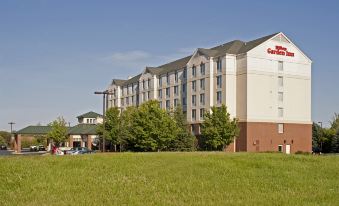 a large hotel with a red and white sign , surrounded by green grass and trees at Hilton Garden Inn Plymouth