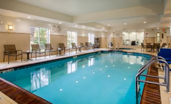 an indoor swimming pool with a large rectangular shape , surrounded by comfortable lounge chairs and mirrors , providing a relaxing atmosphere at Hilton Garden Inn Nashville/Smyrna
