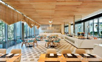 a large , modern dining room with wooden tables and chairs , a bar , and a restaurant setting at Aloft New Delhi Aerocity