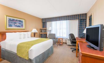 a hotel room with a king - sized bed , a desk , a chair , and a television . the room is clean and well - organized at Ramada by Wyndham Cumberland Downtown