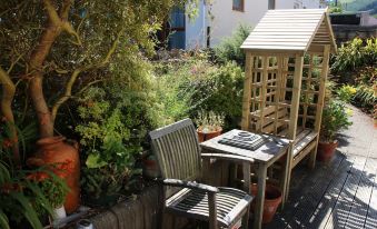a small garden with a wooden gazebo , two chairs , and a table set up for outdoor dining at Acorns Guest House