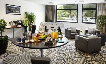 a dining table with a variety of food and drinks , surrounded by chairs in a room with large windows at Best Western Plus Hotel les Rives du Ter