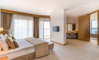 a hotel room with two beds , a television , and a window overlooking the ocean at Grand Hotel Ontur Cesme