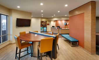 a modern hotel lobby with a large dining table and chairs , a check - in counter , and a tv at TownePlace Suites Clovis