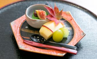 a plate of food with a bowl of fruit and a knife and fork on it at Okushiga Kogen Hotel