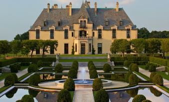 a large , ornate house with a pond in front of it and trees surrounding the area at Oheka Castle Hotel & Estate