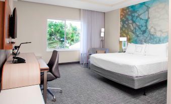 a hotel room with a king - sized bed , a desk , and a window overlooking the outdoors at Courtyard DeLand Historic Downtown