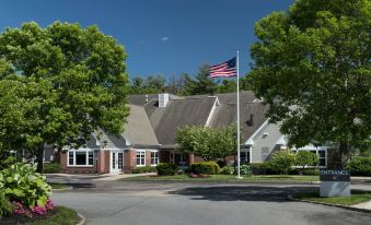 a large house with a flag flying in front of it , surrounded by trees and grass at Residence Inn Boston Westford